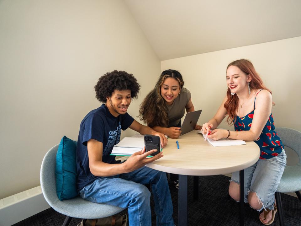 students sitting at a table looking at a cellphone