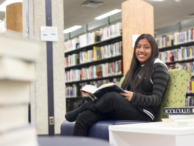 Student reading a book in the Library and Learning Commons.
